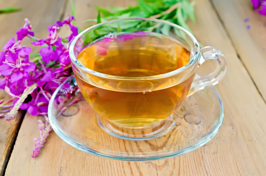 Herbal tea in a glass cup, fresh flowers fireweed on a wooden boards background